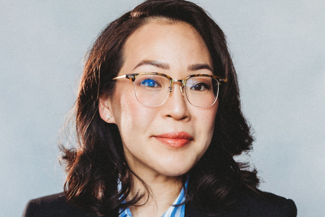 Head-and-shoulders portrait of person in dark blazer and blue striped shirt
