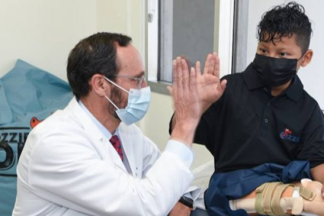 Dr. Anthony Scaduto giving a high five to Efrain Ordonez Jr in an exam room during his appointment to try on his prosthetic leg after undergoing rotationplasty surgery.