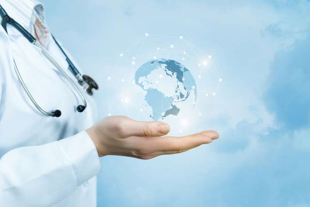 Doctor in white coat and stethoscope holds a digital globe in her hand.U