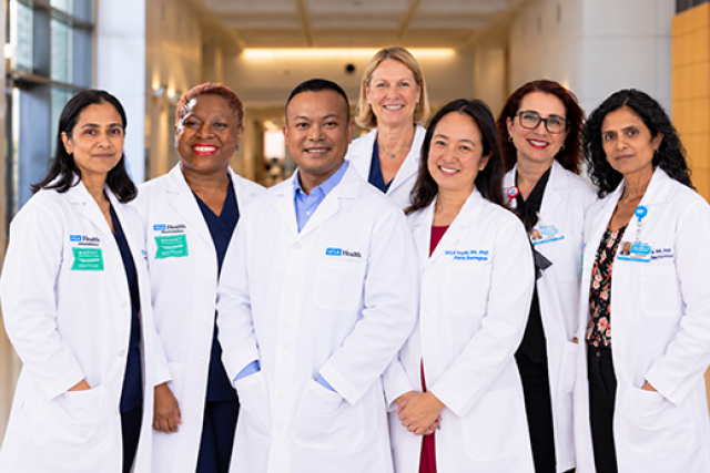 Seven smiling healthcare professionals in white coats standing together