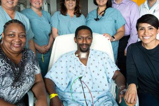 Jonathon Cosby post-surgery sitting in a hospital bed surrounded by his family and care team