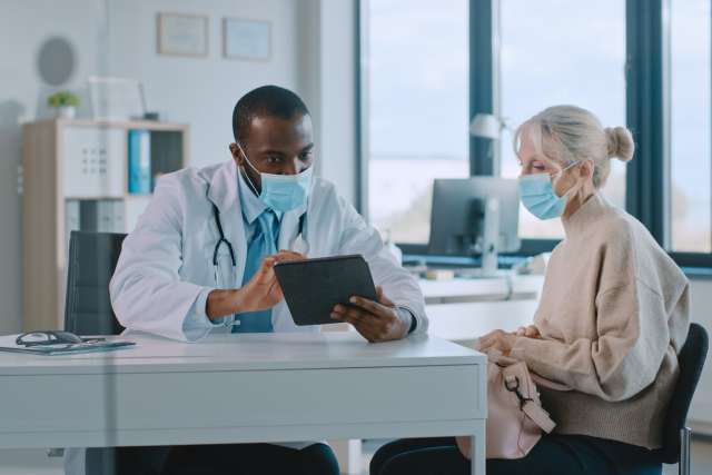 Physician Using Tablet Computer in Hospital Office.