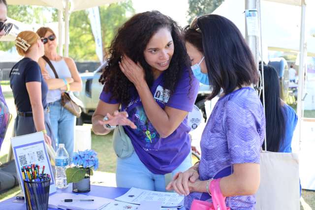 Mirella Diaz-Santos, PhD, speaks with a visitor at the Alzheimer’s Los Angeles "Making Memories Festival" at Los Angeles State Historic Park. 