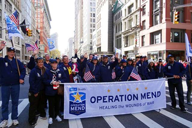 A group of people holding a banner for "Operation Mend" during a parade.