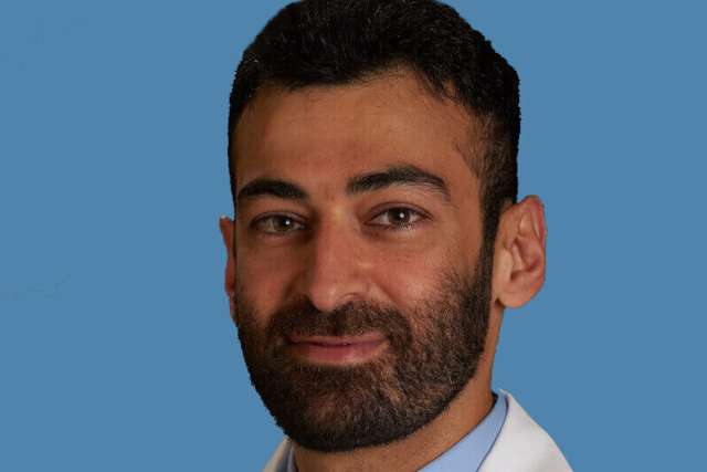 Person in white coat and tie against blue background