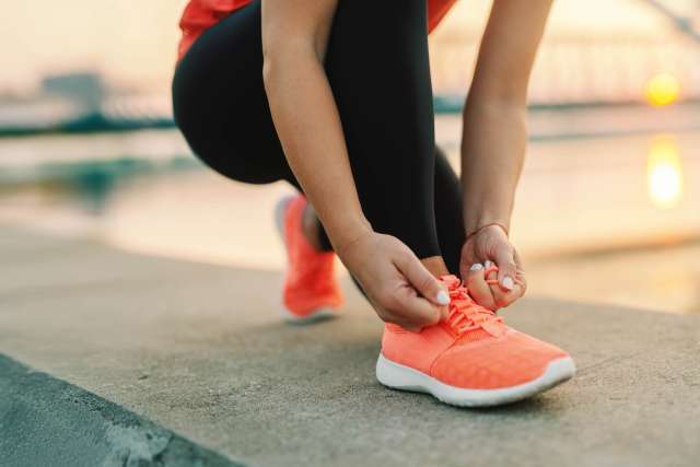 Woman jogger bending down and tying her shoelace