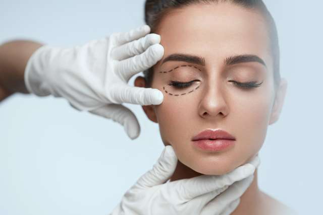 Closeup of Beautician Hands Touching Young Female Patient Face