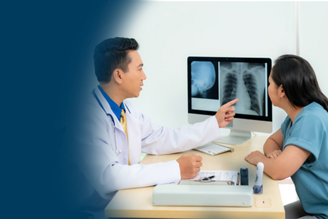An physician pointing at a monitor screen showing a patient a thorax Xray