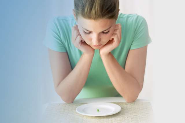 woman looking at a pea on a plate