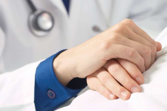 Doctor holding hands of patient