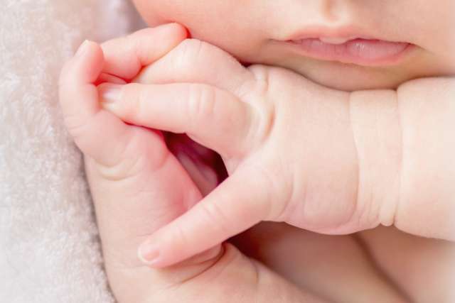 crossed fingers of a newborn baby asleep, closeup