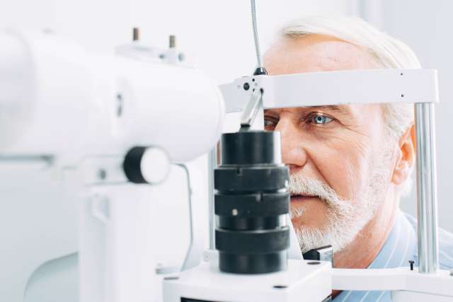 Senior patient checking vision with special eye equipment