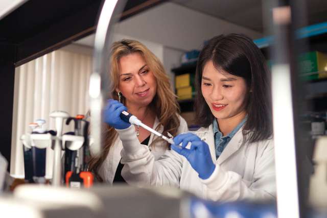Two lab workers at bench looking at a test tube