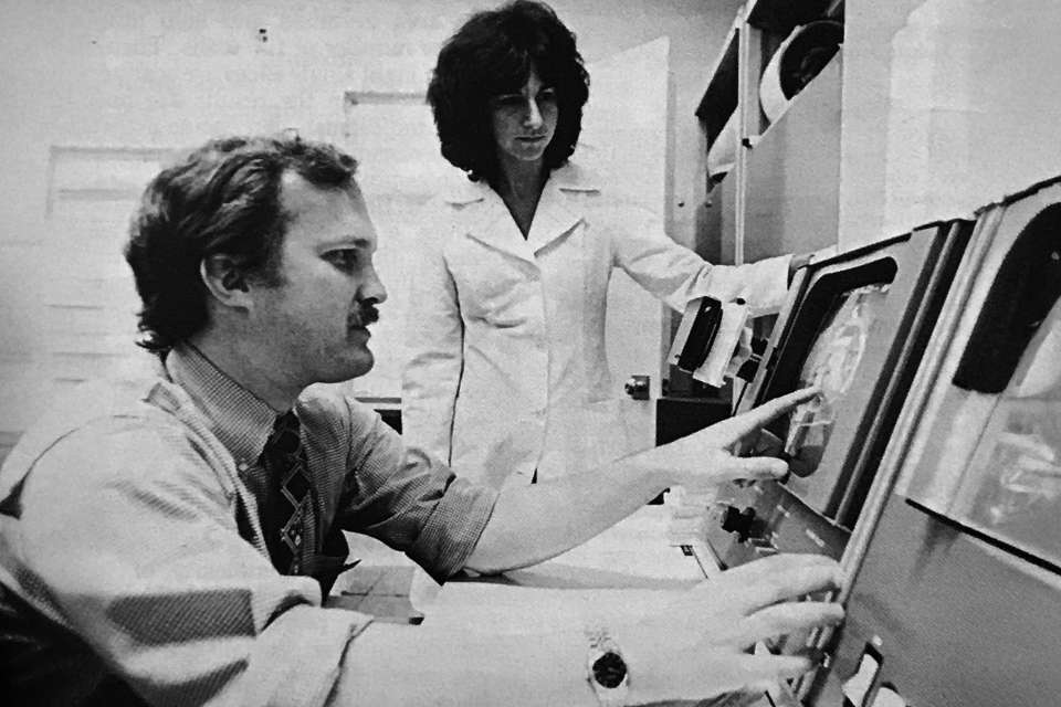 A teacher and student sitting at a computer monitor