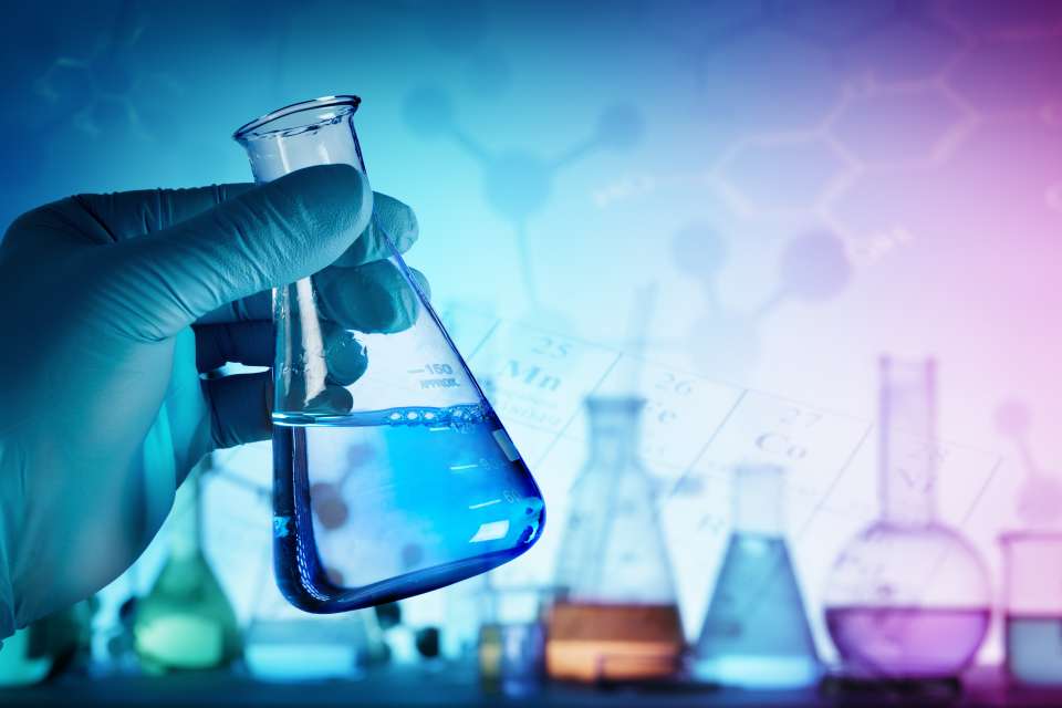 A cancer researcher picking up a beaker