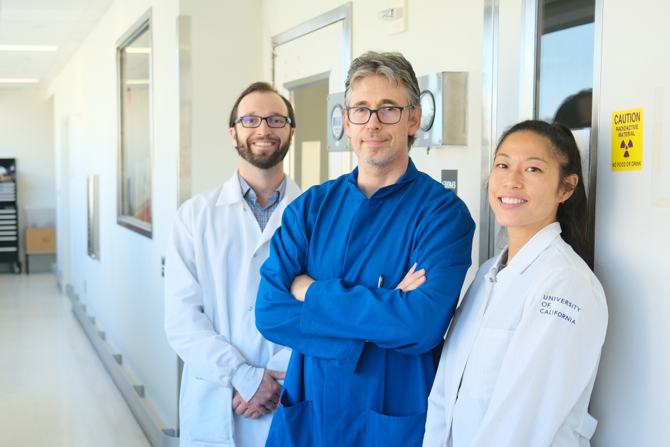 Two male doctors and one female doctor smiling in a hospital hallway