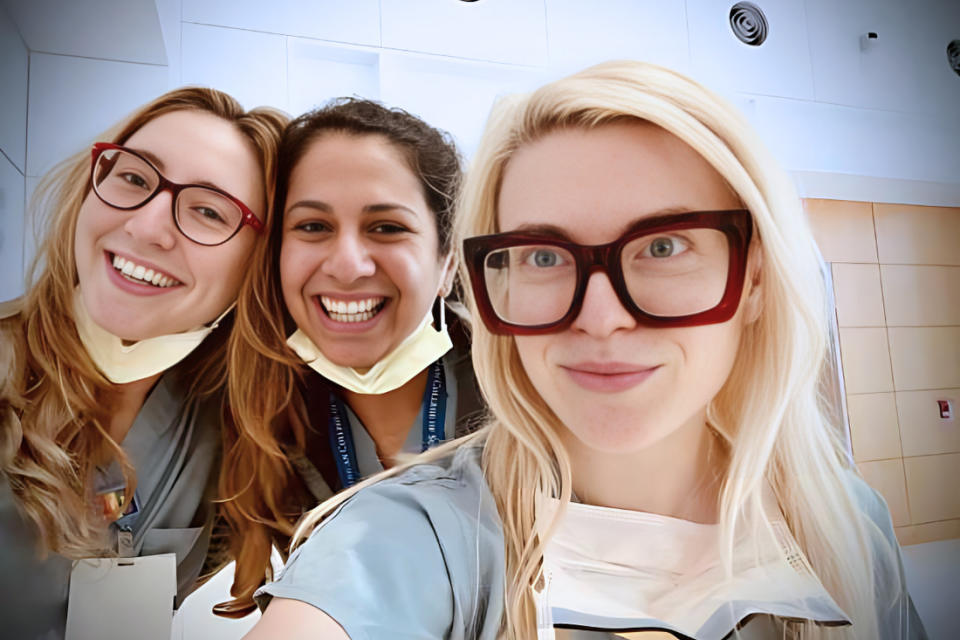 Dr. Christie and two residents taking a selfie wearing gray scrubs.