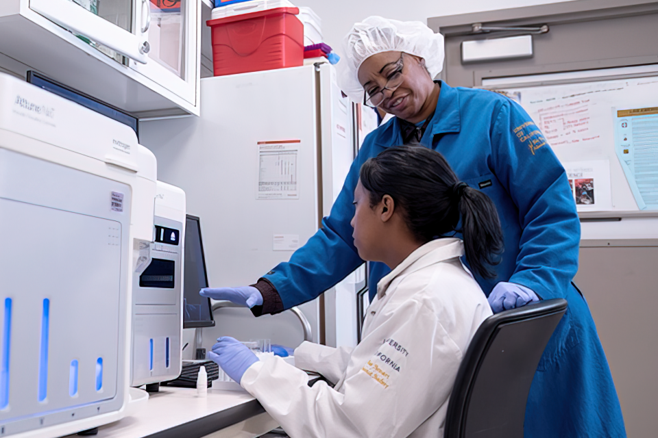 Two people using the Flow cytometry equipment in the UCLA Health Flow Cytometry Shared Resource laboratory, used for advanced cell analysis.