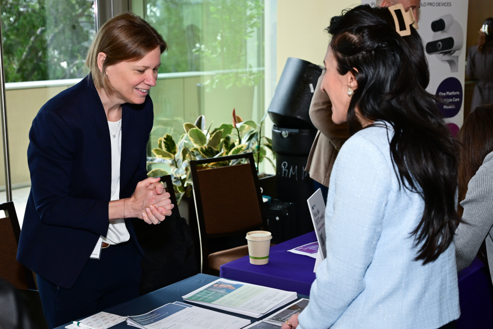 Person behind an information table speaking with two attendees over brochures