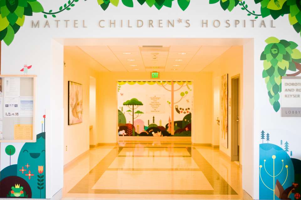 A hallway in the UCLA Mattel Children's Hospital features colorful decorations and a sign for the hospital.