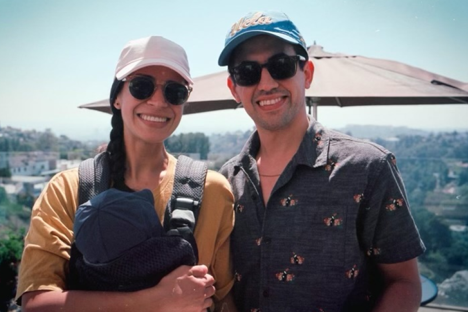 a man and woman wearing a hat and sunglasses outside, smiling and posing