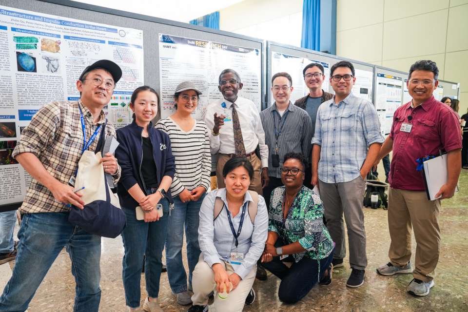 group of Abel Lab members posing for a group photo at DoM Research Day 2024 event with research poster presentations in the background
