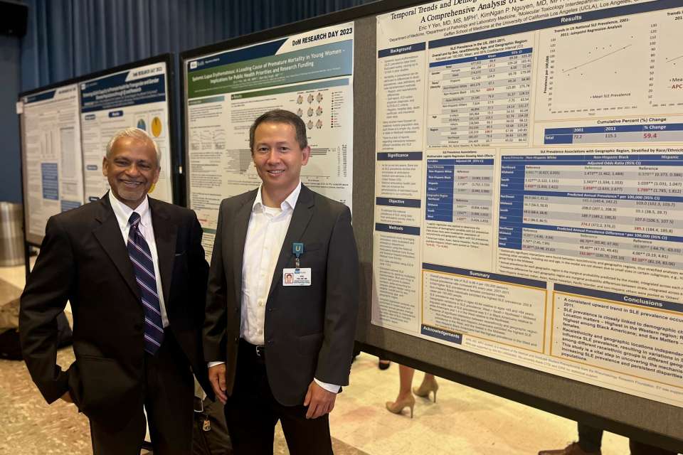Smiling men in front of posters.