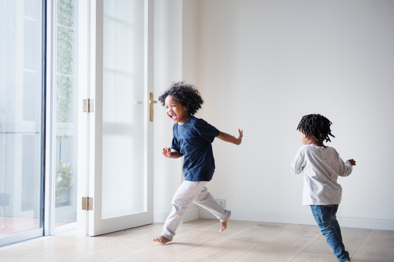 Two young children chasing each other inside of a room