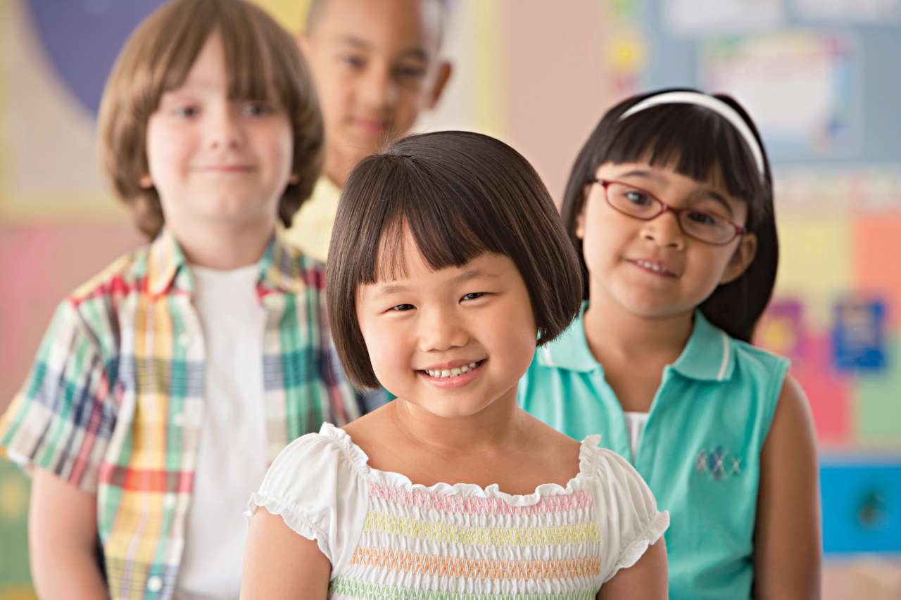 Three children smiling together in a classroom