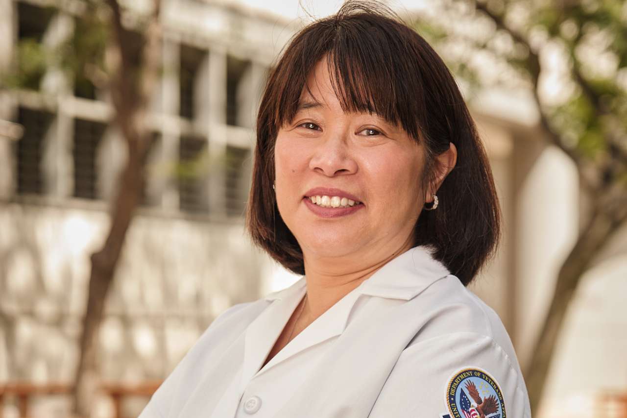 Dr. Cathy Lee, standing with arms crossed, smiling outside.