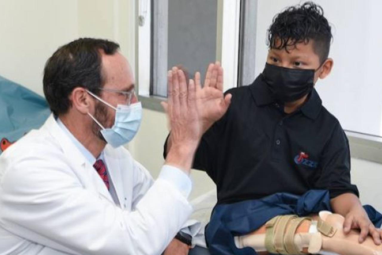 Dr. Anthony Scaduto giving a high five to Efrain Ordonez Jr in an exam room during his appointment to try on his prosthetic leg after undergoing rotationplasty surgery.