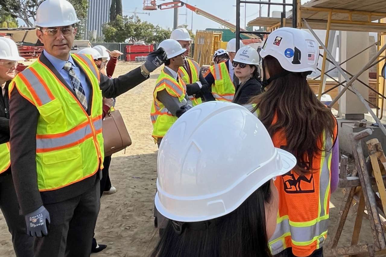 Chief Operating Officer Richard Azar, left, and others wearing hard hats view the mock-up of an exterior wall at the neuropsychiatric hospital construction site.