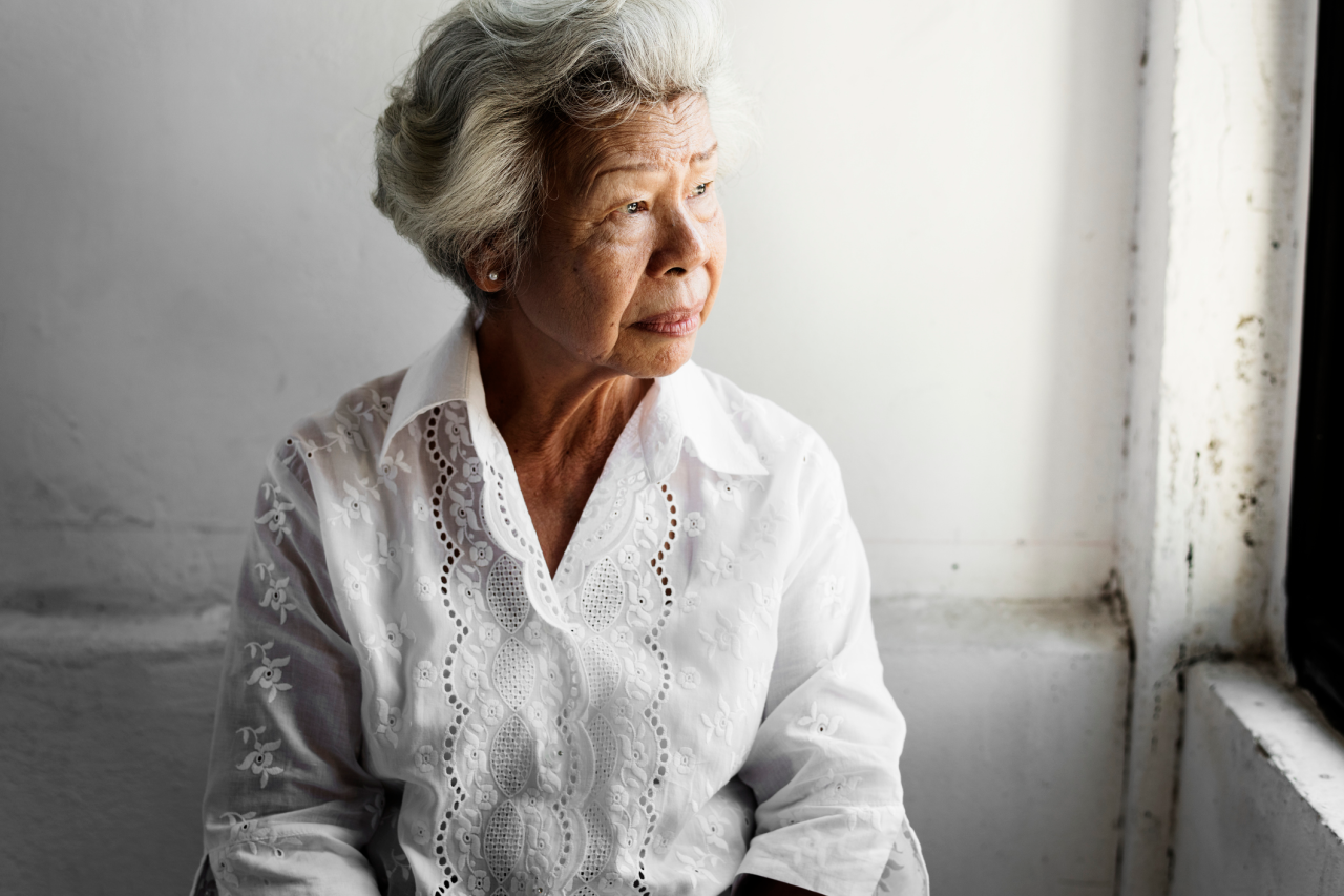 An older woman looking outside of a window