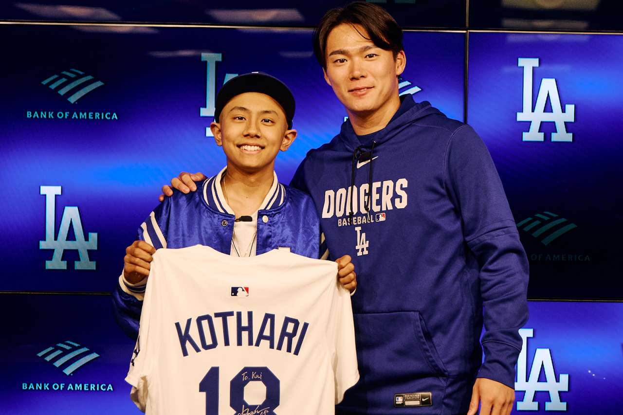 A teen oncology patient holding a baseball jersey poses for a photo with a Dodgers pitcher.