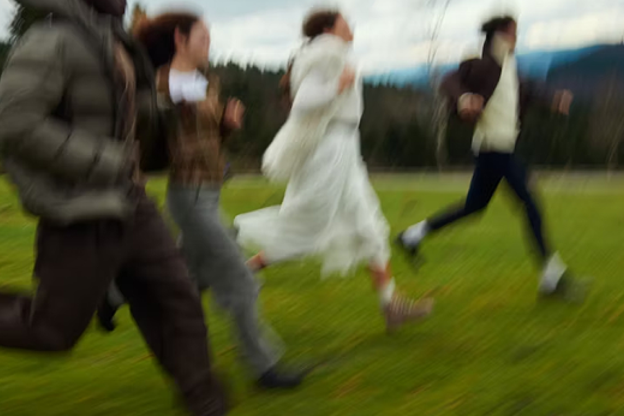 a blurred perspective of four people running in the grass