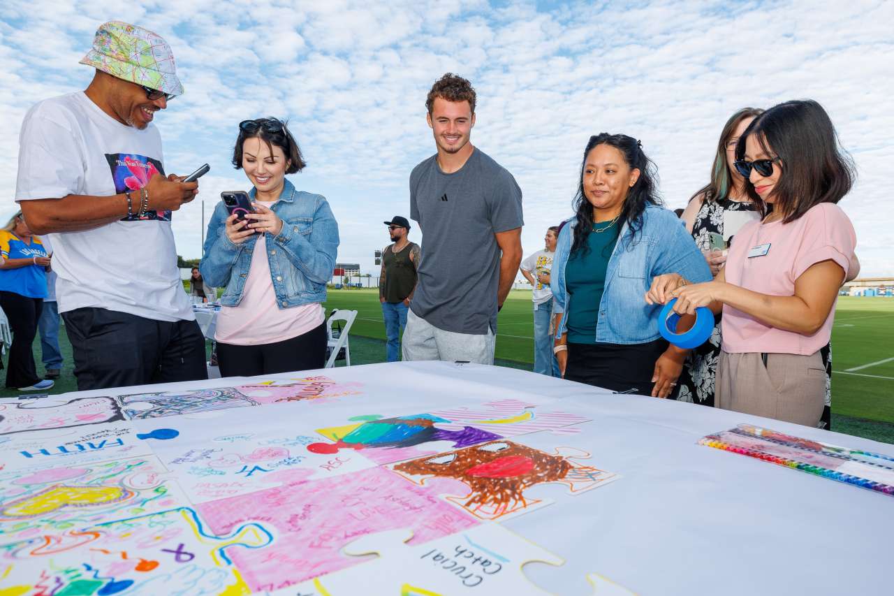 Chargers wide receiver Ladd McConkey looks at the Crucial Catch mosaic with guests.