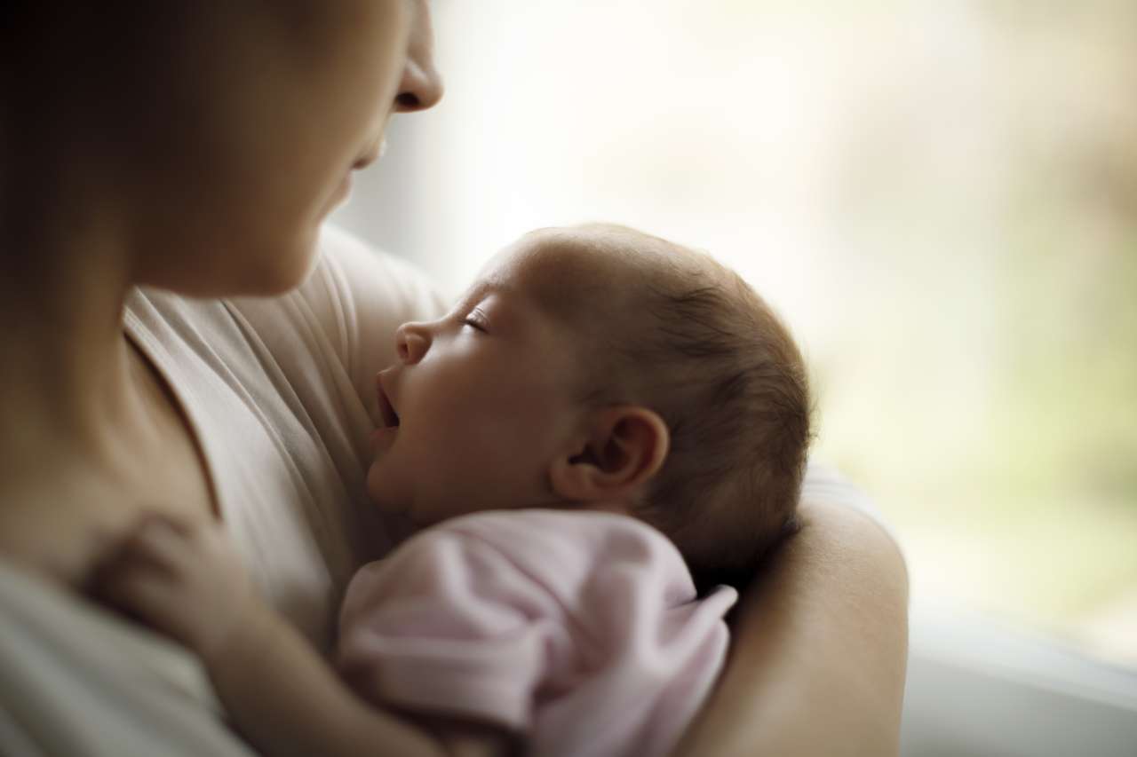 Baby nursing at parent's breast, cradled against chest.