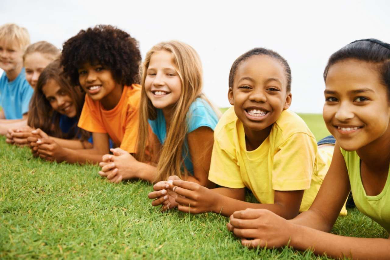 Children laying on the grass and smiling