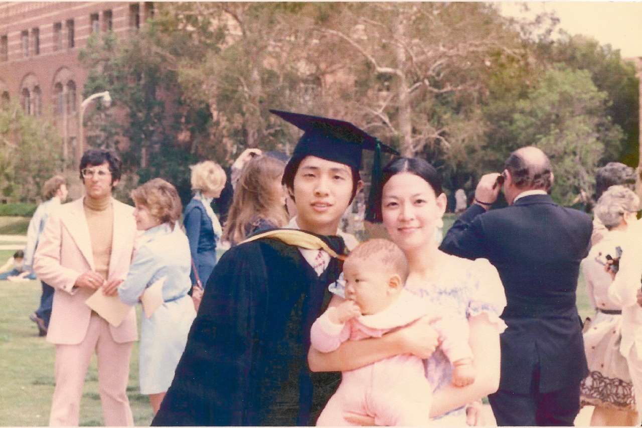 Dr. Ka-Kit Hui is shown in cap and gown from his UCLA medical school graduation, with his wife, who is holding baby Ed Hui.