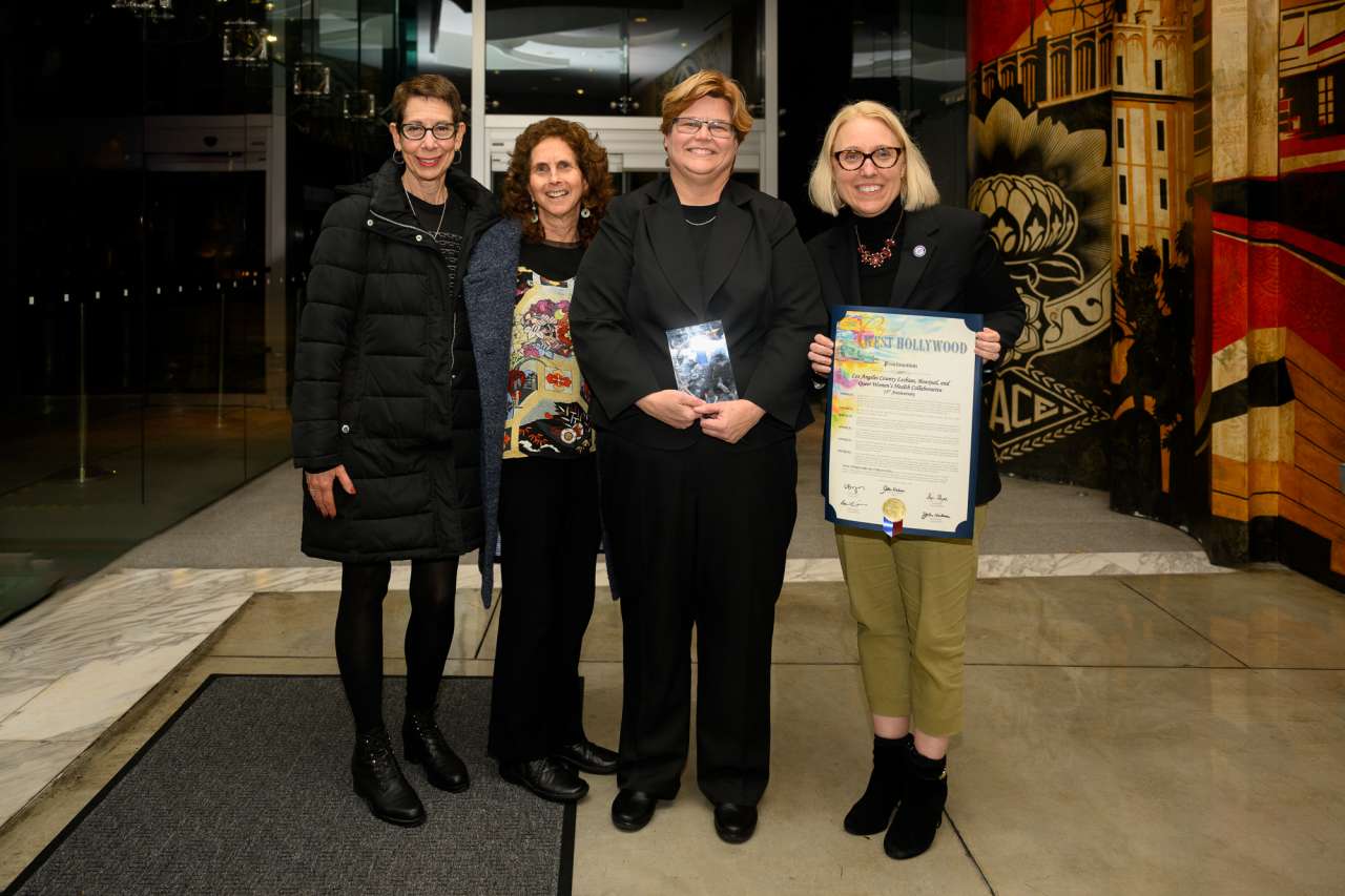 Four individuals standing with a certificate