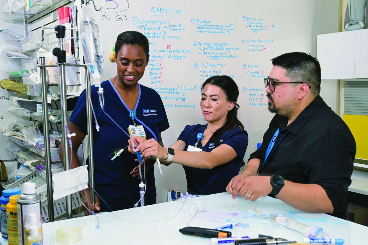 Three nursing professionals collaborate on equipment in a medical setting.