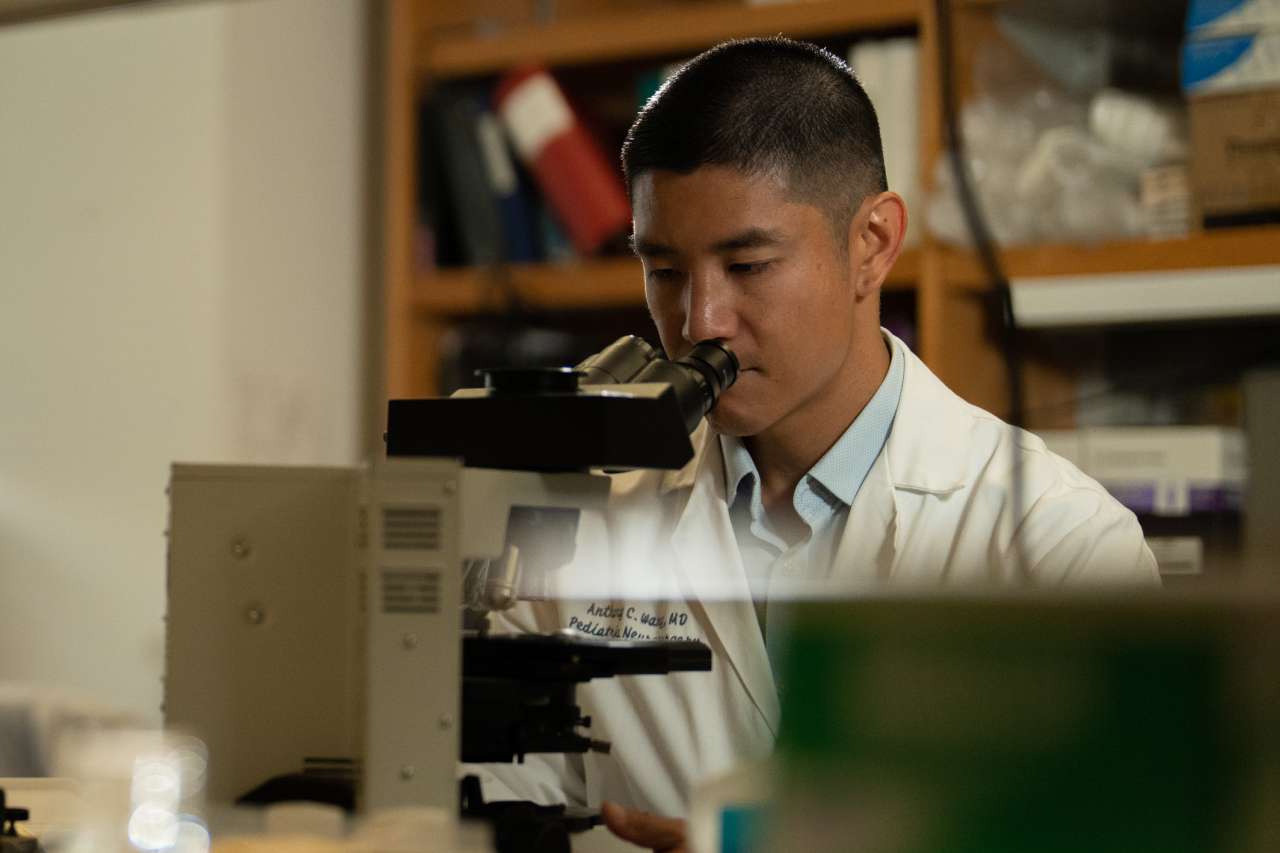 Dr. Anthony Wang looking into a microscope. 