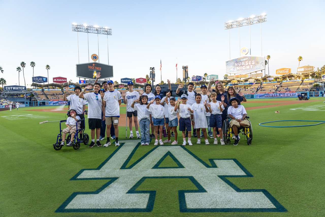 A group of patients pose for a photo on the field at Dodger Stadium in honor of Children Cancer Awareness Month