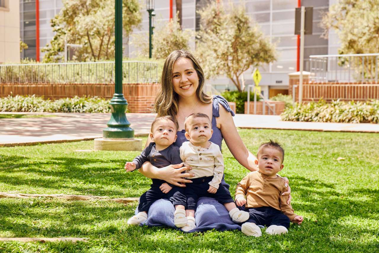 A mom sits with her identical triplet boys.