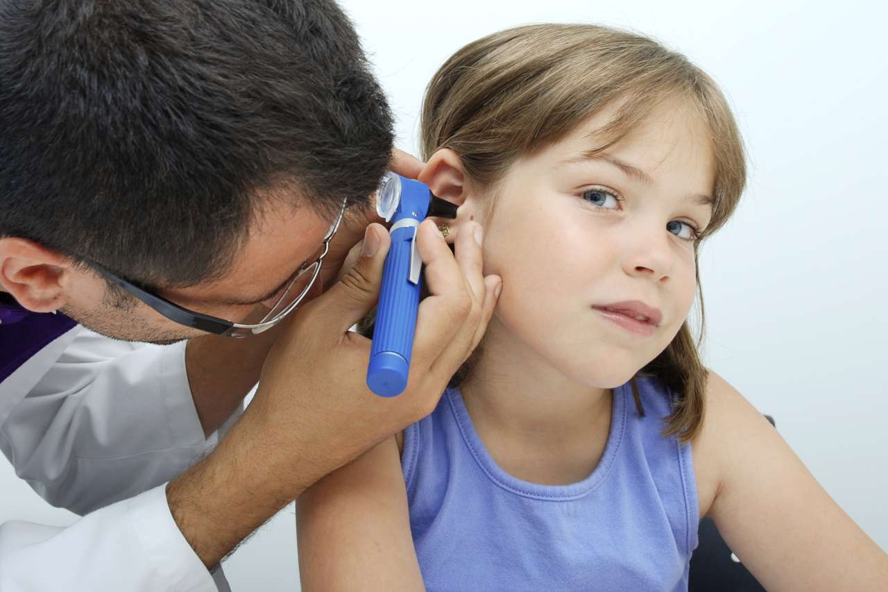 Adult examining child's ear with otoscope
