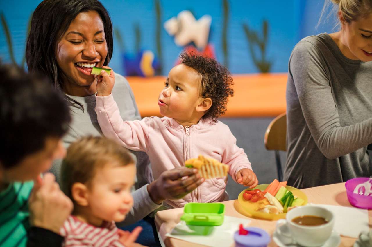 A group of mothers seated at a table engaging with their babies