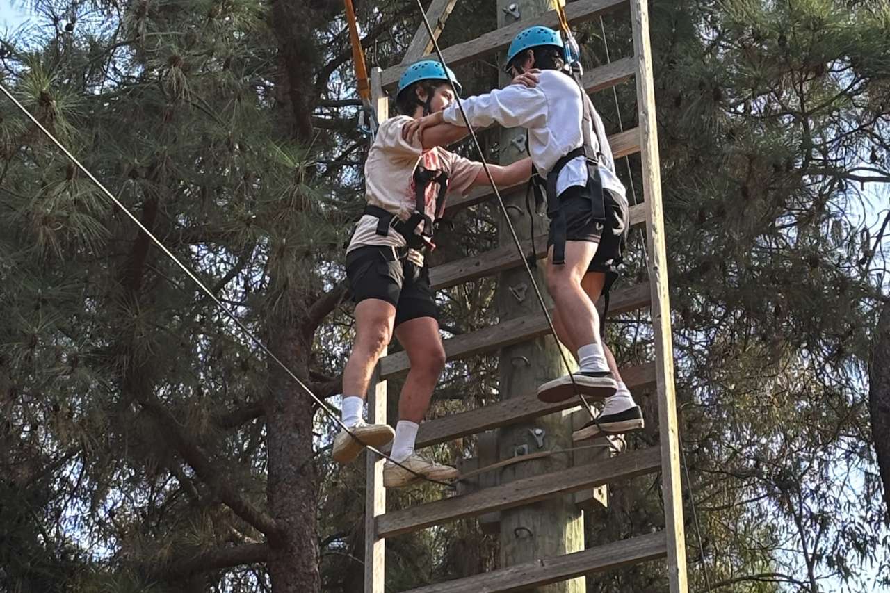 two Internal Medicine Residents on a high tight-rope leaning on each other for balance