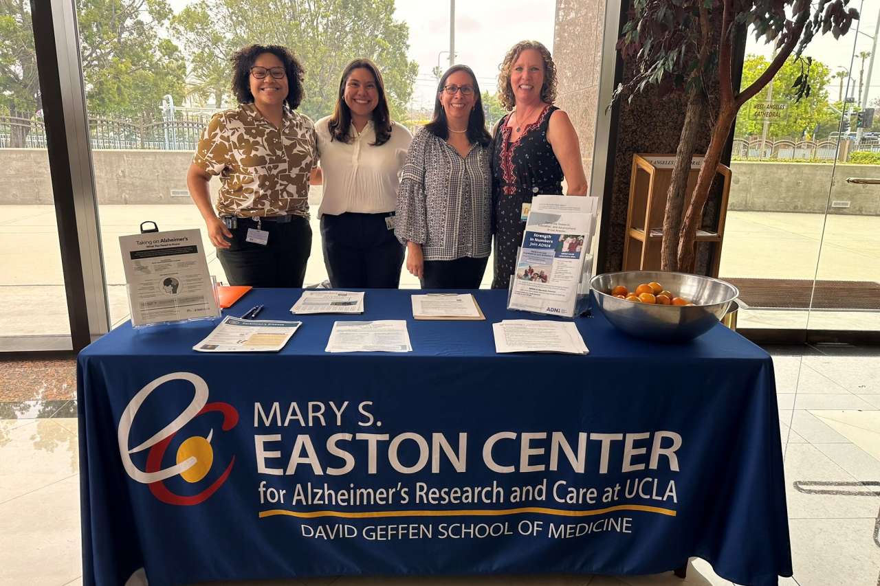 Four members of the Mary S. Easton Center staff pose at an information table during the Faith & Healing luncheon at West Angeles Church.