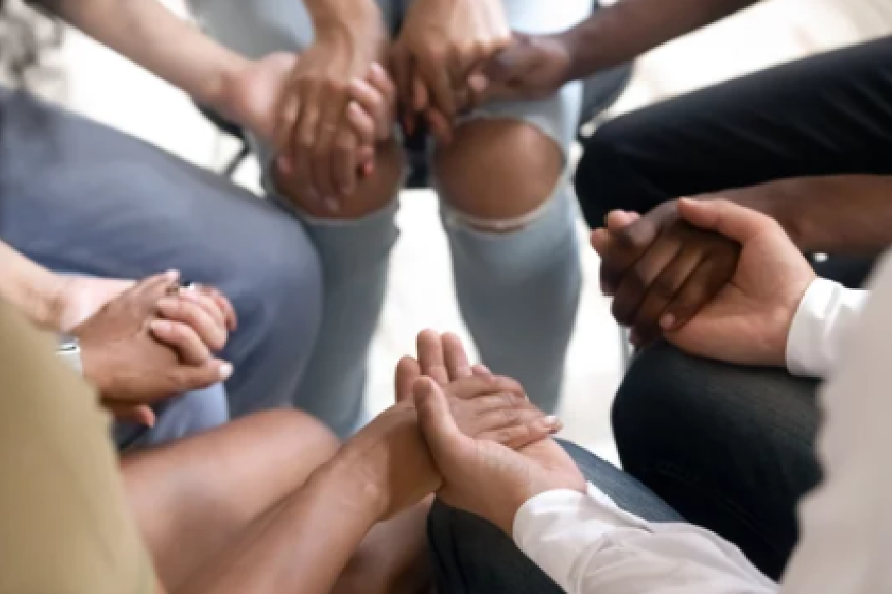 5 people sitting in a circle and holding hands