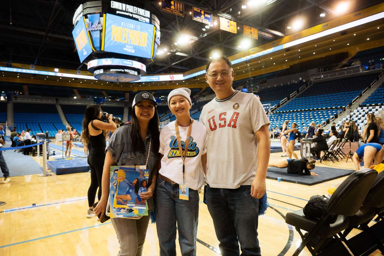 A patient and her parents stand near the gymnastics floor.